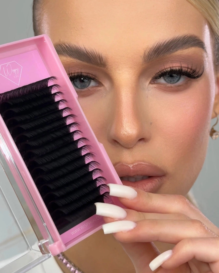 zbliżenie na pasek rzęs wysokoporowatych Essential Collection Wispy Kiki w różowym pudełku przy twarzy modelki