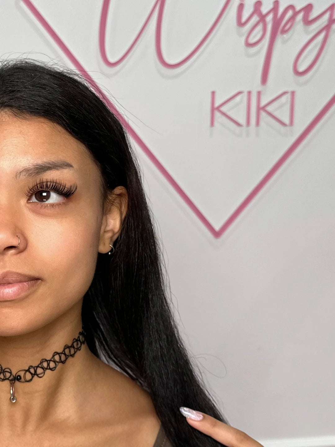 Naturalna stylizacja z rzęs Wispy Kiki Essential Collection na tle różowego logo Wispy Kiki